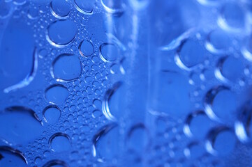 Abstract blue background. Drops of water on a plastic bottle.