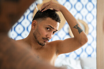 Man applying hair product in a hotel room mirror