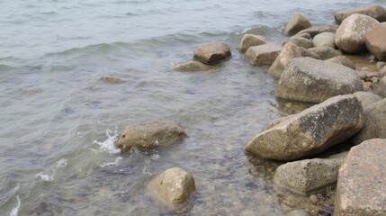 Obraz premium Tranquil Shoreline Scene with Rocks and Gentle Waves at Water's Edge