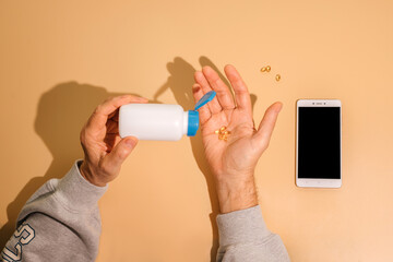 Senior man hands holding a bottle with pills and shaking out several.