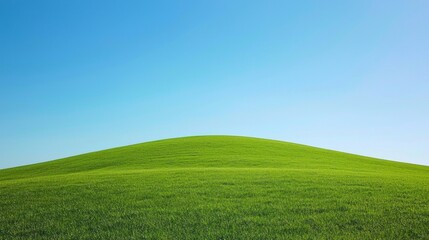 Obraz premium A lush green hill rises gently against a backdrop of a pristine blue sky, radiating peace and serenity. This vibrant landscape offers a perfect escape into nature's embrace