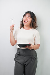 Beautiful young asian woman with wavy hair wearing white shirt is writing on a tablet screen using...