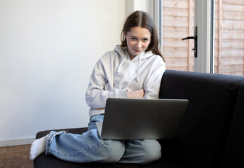 Naklejka premium Girl sitting on sofa with laptop