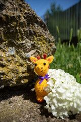 Beautiful knitted toy of a yellow giraffe near hydrangea flowers, knitted toys, handmade