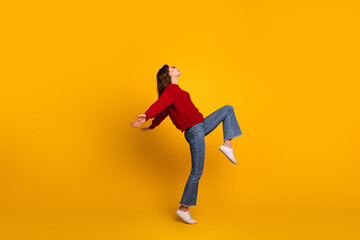 Cheerful Young Woman in Red Sweater Striking Energetic Pose Against Vibrant Yellow Background