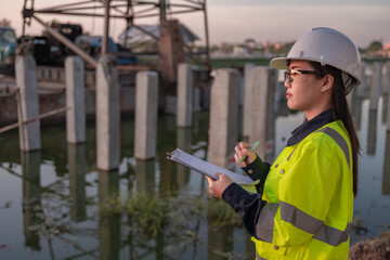 Obraz premium Civil Engineers Consult on Pile Driving in Water,Working at site of a large building project Construction Site Collaboration,Discuss Construction Project,Building Foundations at the Site