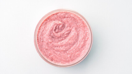 Pink body scrub in an open jar from above On a white background.