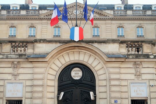 Fa&ccedil;ade du b&acirc;timent de la Caisse des D&eacute;p&ocirc;ts et Consignations (CDC) &agrave; Paris, h&ocirc;tel de Belle-Isle, avec des drapeaux fran&ccedil;ais et europ&eacute;ens &ndash; septembre 2024 (France)