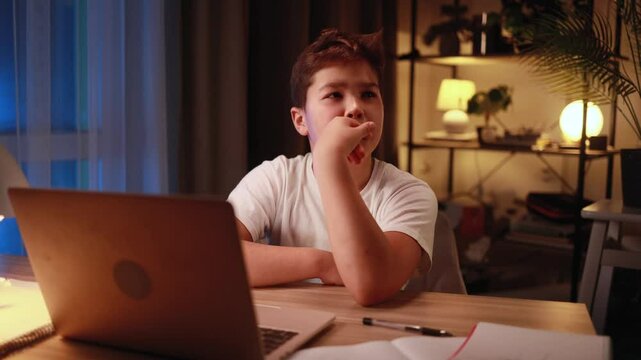 Portrait of cute little boy studying thinks questioningly about difficult choice choose imagine plan in mind has doubts late at night at home workplace	