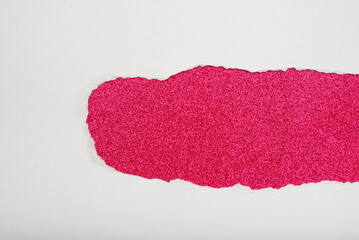 Torn white paper revealing a dark pink glitter background.
