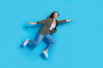 Joyful young woman wearing casual clothes posing with excitement against a vibrant blue background