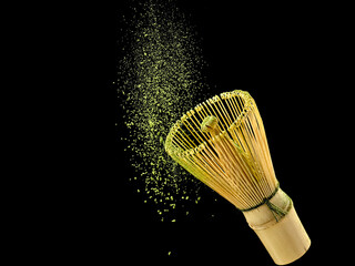Bamboo matcha whisk with flying powder on black background, studio shot