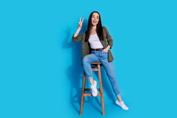 Charming young woman posing confidently on a bright blue background, expressing joy and style