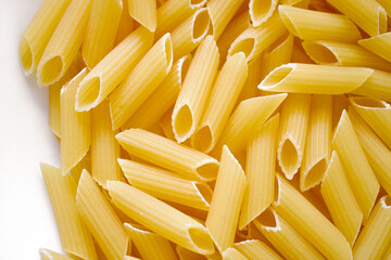 Uncooked penne pasta on a white plate.