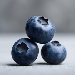 Three blueberries balanced, close-up, grey background, food photography