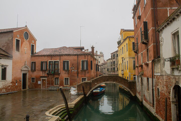 Small low bridge crossing a canal in Venice and a street with facades of old residential houses, Italy, Veneto region