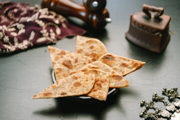 Deliciously prepared roti sits on a rustic plate, showcasing traditional Indian cuisine. Surrounding it are cultural elements that enhance the warm, inviting atmosphere