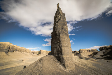 Towering Desert Spire Under Cloudy Sky