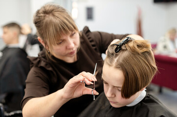 Professional hairstylist carefully cutting a young client's hair in a modern salon setting