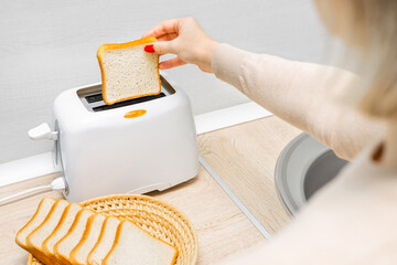 woman's hand putting bread into the toaster. housewife frying bread in a toaster, in the kitchen. woman making toast. toast bread in a toaster. 