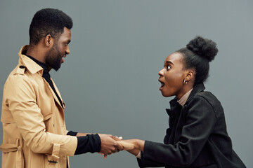 Excited couple sharing joyful moment, surprised expressions, modern fashion, emotional connection, gray background, perfect for relationship concepts