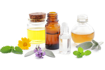 Variety of aroma essential oils in glass bottles with aromatic flowers: lavender, sage, melissa isolated on white background, copy space, natural cosmetic banner, aromatherapy and spa concept