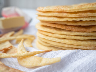 A pile of baked thin round buttery layers, dough scraps and butter on a white waffle towel ready to make a shortcrust puff pastry Napoleon cake.