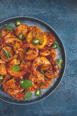 grilled shrimp, unpeeled, headless, with spices, on a dark blue table, homemade, no people,