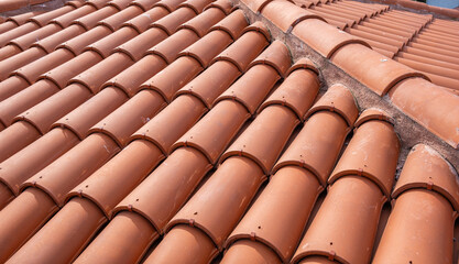 Traditional terracotta red roof tiles. Classic and durable roofing. Old and used overlapping patterns of warm terracotta house red clay tiles used in residential. Material texture