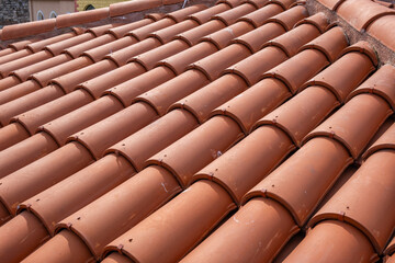 Traditional terracotta red roof tiles. Classic and durable roofing. Old and used overlapping patterns of warm terracotta house red clay tiles used in residential. Material texture, close up
