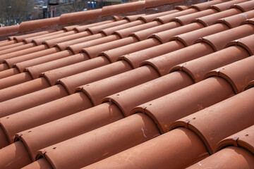 Traditional terracotta red roof tiles. Classic and durable roofing. Old and used overlapping patterns of warm terracotta house red clay tiles used in residential. Material texture, closeup