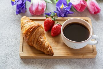 Happy mother's day, beautiful breakfast, lunch with cup of coffee (cappuccino) fresh croissants, strawberries on tray, bouquet of tulips as gift. Festive concept. Spring holiday, family relations.