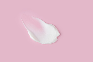 Texture of white face cream on pink background