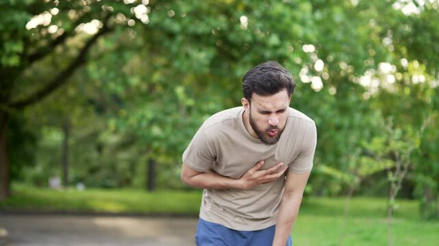 Sportsman suffered a heart attack or chest pain during a run in park. He clutches his chest in pain and massages it with his hand. Tired athlete suffers from tension in the heart. Health care concept