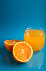 photo Refreshing Glass of Vitamin-C Rich Orange Juice with Freshly Sliced Orange Halves on a Vibrant Blue Background: Perfect Boost for Immune System and Overall Health