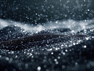A macro photograph capturing fine black sand with shimmering particles and scattered water droplets, creating an abstract and mesmerizing texture