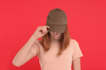 Woman in stylish baseball cap on red background. Mockup for design