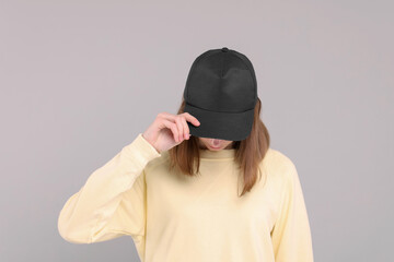 Woman in stylish baseball cap on grey background. Mockup for design