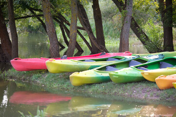Many canoes of different colors on the river bank before training without people. Boating on the...
