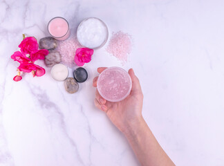 Woman hand holding natural body scrub in a spa salon. Natural body care products, relaxation, detox, aromatherapy, beauty, wellness, organic, spa concept. Closeup