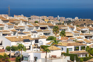 Mediterranean coastal townhouses with terracotta roofs and palm trees, overlooking the sea.