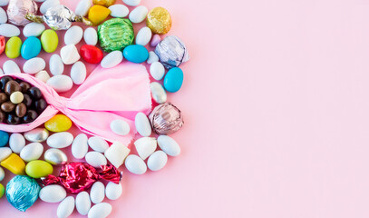 Obraz premium Colorful almond candies and chocolates designed in the shape of candy bonbon on a pink surface with large copy space