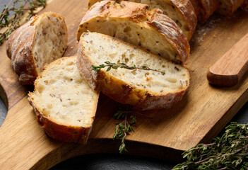 Sliced ​​baguette with flax and spices on a wooden cutting board