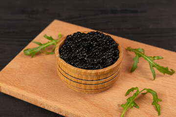 Bowl with black caviar on on wooden table