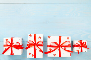 Gift boxes with red hearts on wooden background, top view
