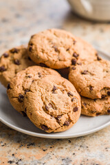 Chocolate chip cookies on plate on kitchen table.
