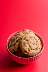 Chocolate chip cookies in bowl on red background.