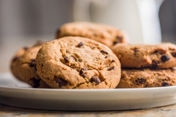 Chocolate chip cookies on plate on kitchen table.