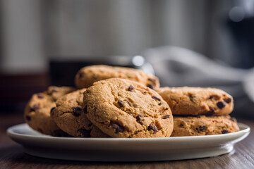 Chocolate chip cookies on plate on wooden table.