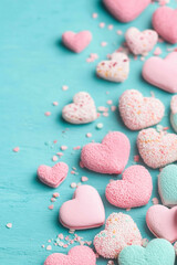 Obraz premium A colorful display of heart-shaped candies in pink, white, and blue, scattered across a teal surface.